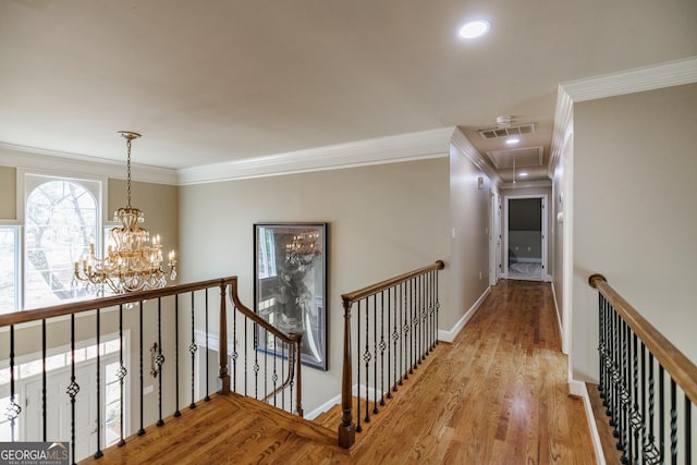 corridor with an upstairs landing, attic access, and crown molding