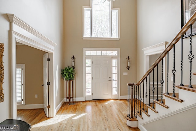 entrance foyer featuring a high ceiling, a wealth of natural light, and wood finished floors