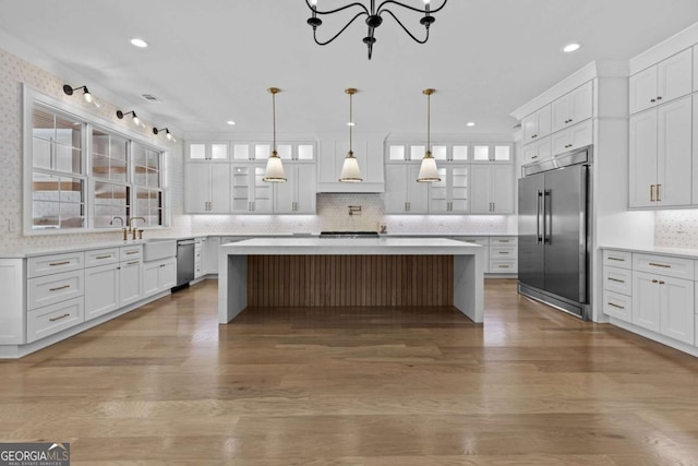 kitchen with white cabinetry, wood finished floors, stainless steel appliances, and light countertops