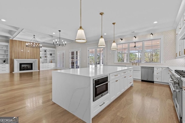 kitchen featuring light wood finished floors, a fireplace, a center island, appliances with stainless steel finishes, and coffered ceiling