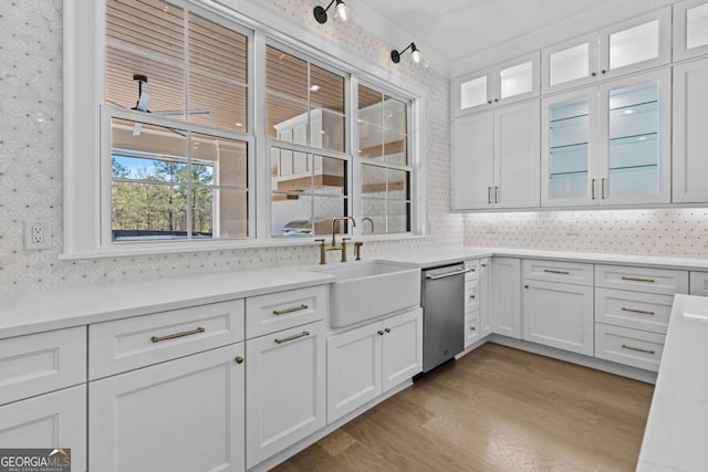 kitchen featuring light wood-type flooring, white cabinets, a sink, and dishwasher