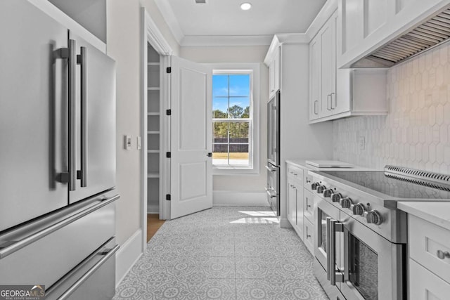kitchen featuring white cabinetry, light countertops, ornamental molding, under cabinet range hood, and high quality appliances