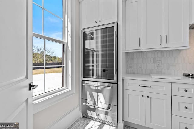 kitchen with decorative backsplash, light countertops, white cabinets, and beverage cooler