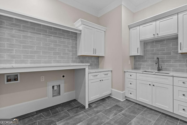 kitchen featuring white cabinetry, light countertops, decorative backsplash, and a sink