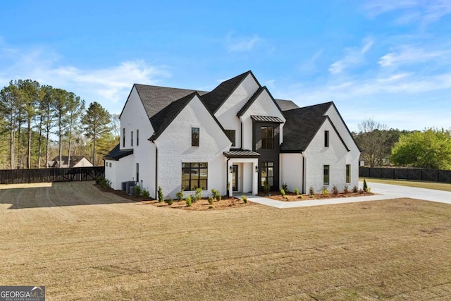 view of front of house with metal roof, a standing seam roof, a front lawn, and fence