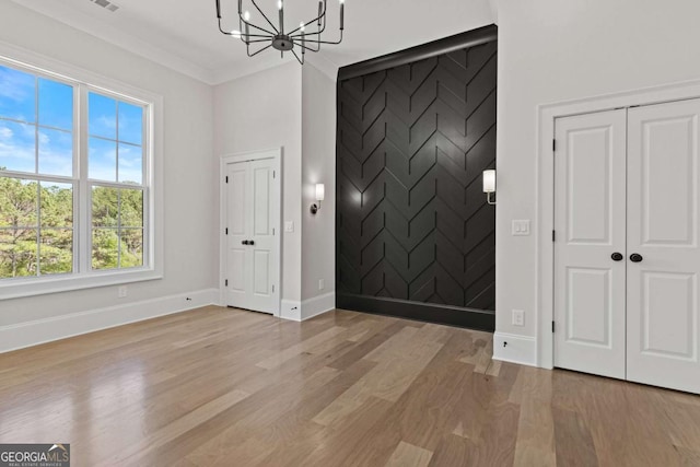 interior space featuring a notable chandelier, an accent wall, light wood-style flooring, baseboards, and visible vents