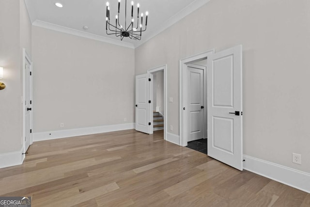 unfurnished dining area featuring baseboards, ornamental molding, wood finished floors, recessed lighting, and a notable chandelier