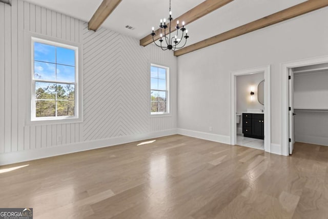 unfurnished bedroom with multiple windows, beamed ceiling, wood finished floors, and an inviting chandelier