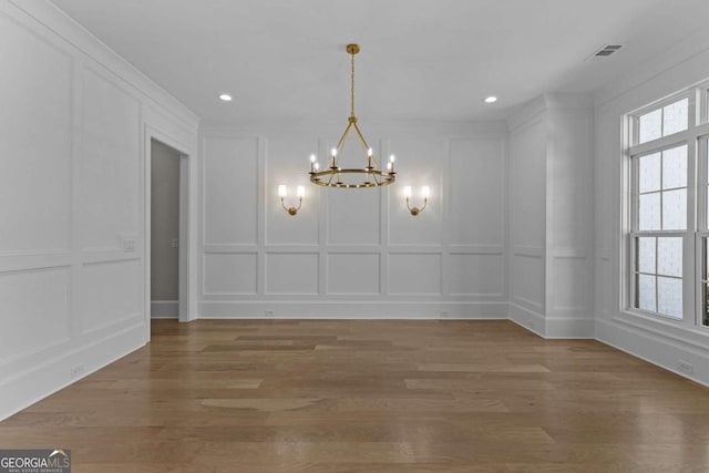 unfurnished dining area featuring an inviting chandelier, a decorative wall, and visible vents
