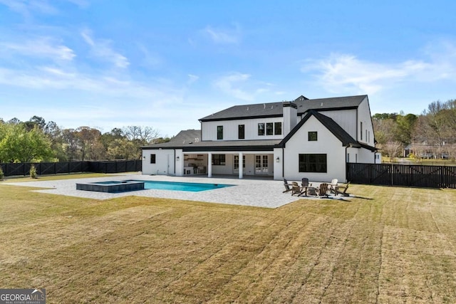 rear view of house featuring a fenced backyard, a pool with connected hot tub, a yard, and a patio area