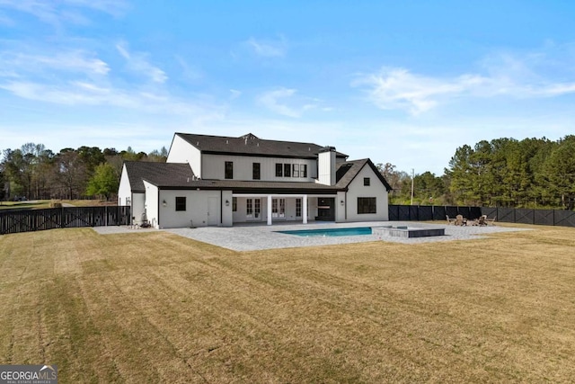 back of house featuring a lawn, a fenced backyard, a pool with connected hot tub, and a patio area