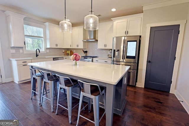 1494 Addison Pl, Decatur, GA 30033 - kitchen featuring appliances with stainless steel finishes, wall chimney exhaust hood, a kitchen island, white cabinetry, and light countertops