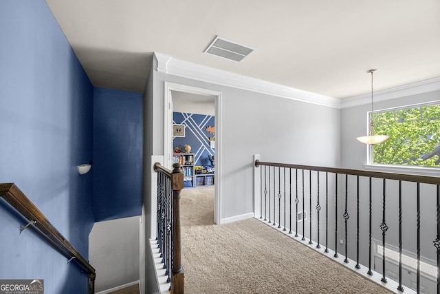 hall with baseboards, visible vents, carpet, an upstairs landing, and crown molding