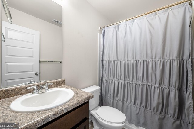bathroom featuring curtained shower, visible vents, toilet, and vanity