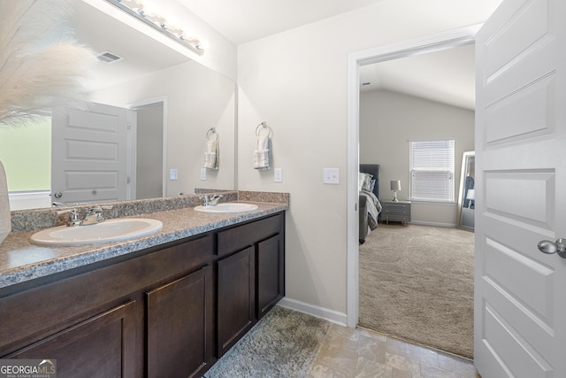 bathroom featuring lofted ceiling, visible vents, a sink, and double vanity