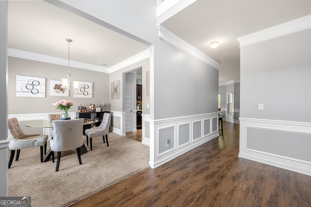 dining room featuring crown molding, dark wood-style floors, a notable chandelier, and wainscoting