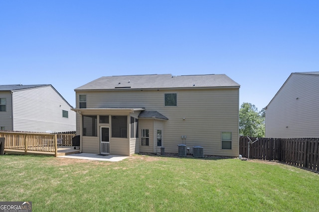 rear view of house featuring a lawn, a fenced backyard, a sunroom, and central AC