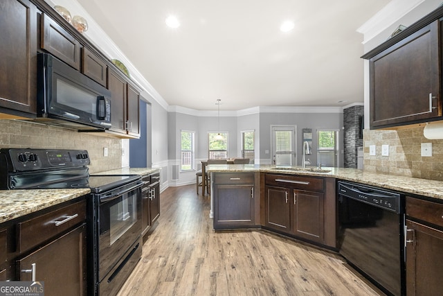 kitchen featuring a wealth of natural light, a sink, dark brown cabinetry, light wood-style floors, and black appliances