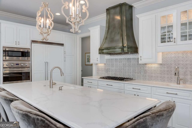 kitchen featuring built in appliances, white cabinetry, a sink, and premium range hood