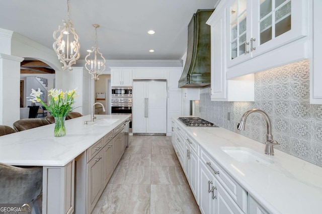 kitchen featuring built in appliances, a chandelier, extractor fan, and a sink