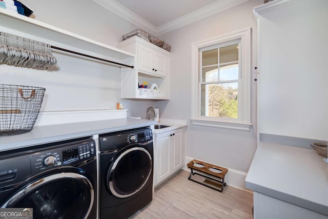 laundry area featuring cabinet space, a sink, baseboards, ornamental molding, and washer and dryer