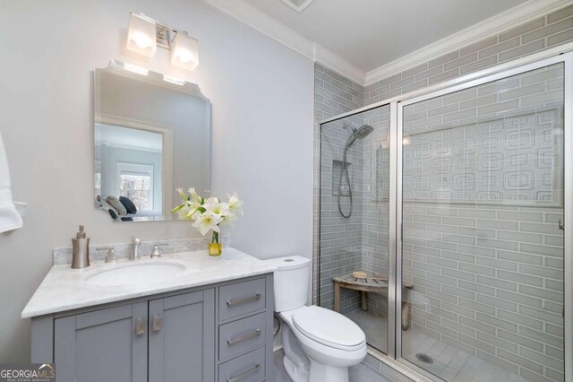 bathroom with vanity, ornamental molding, a stall shower, and toilet