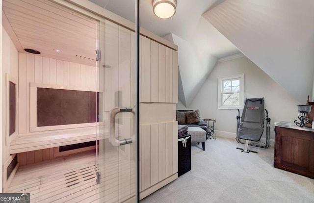 office area featuring baseboards, vaulted ceiling, and light carpet