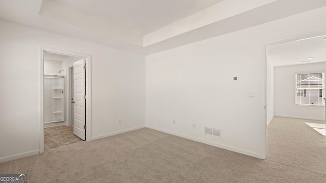 interior space featuring a raised ceiling, visible vents, and carpet floors