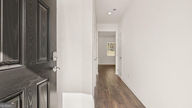 hallway featuring dark wood-style flooring and baseboards