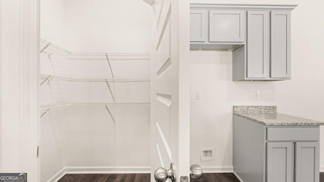 interior space featuring laundry area, baseboards, and dark wood finished floors
