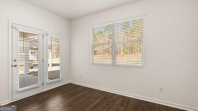 empty room with dark wood-type flooring and baseboards