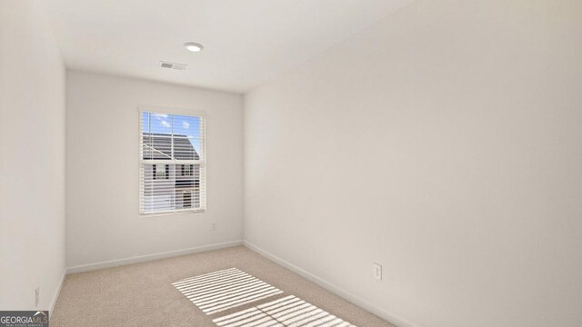 empty room featuring visible vents, baseboards, and carpet