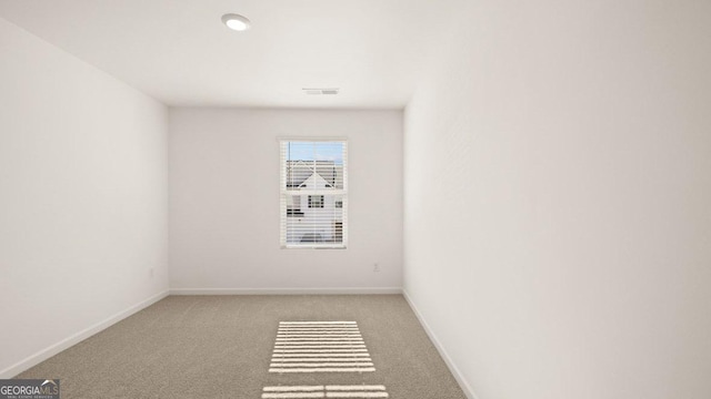 carpeted spare room featuring baseboards and visible vents