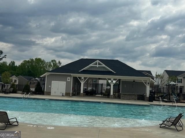 community pool featuring a patio, fence, and an outbuilding
