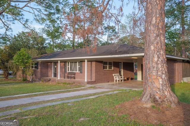 single story home with an attached carport, brick siding, a front lawn, and concrete driveway