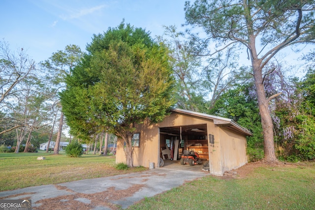exterior space featuring a garage, concrete driveway, a front yard, an outbuilding, and an outdoor structure