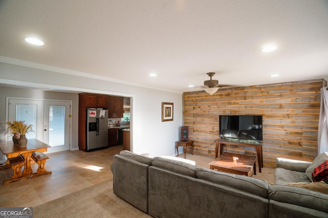 living area with crown molding, an accent wall, a ceiling fan, wood walls, and recessed lighting