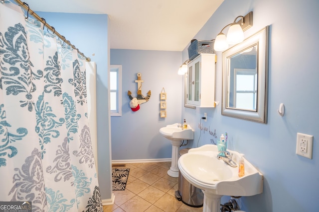 bathroom with a shower with curtain, tile patterned floors, baseboards, and a healthy amount of sunlight
