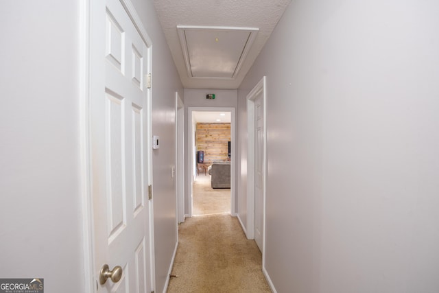corridor featuring attic access and light colored carpet
