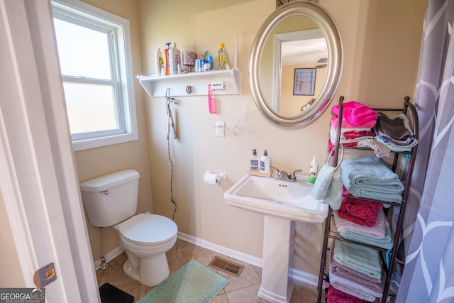 bathroom with toilet, a sink, tile patterned flooring, baseboards, and visible vents
