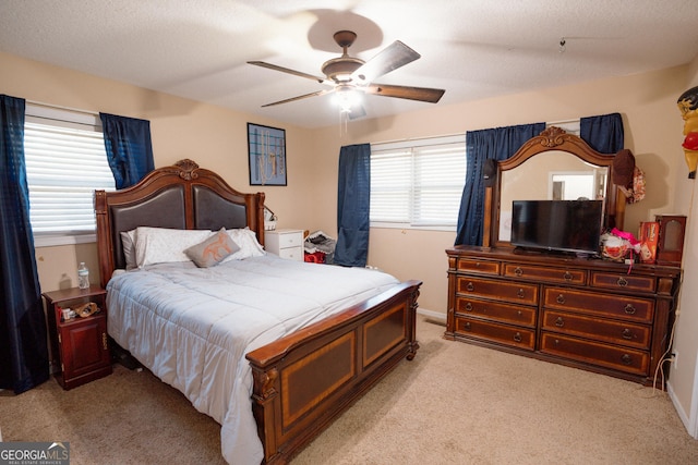 bedroom with baseboards, a textured ceiling, ceiling fan, and light colored carpet
