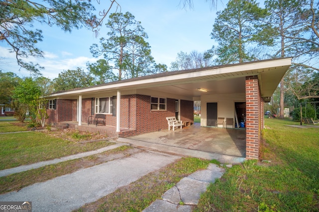 ranch-style house featuring a front yard, brick siding, an attached carport, and driveway