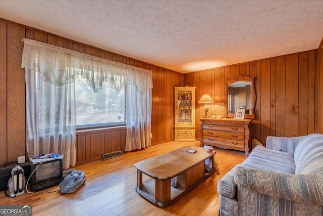 254 E Girard Ave, Cedartown, GA 30125 - living room featuring a textured ceiling, light wood-type flooring, and wood walls