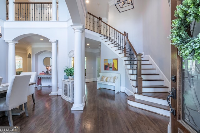 entrance foyer featuring crown molding, wood finished floors, a towering ceiling, and plenty of natural light