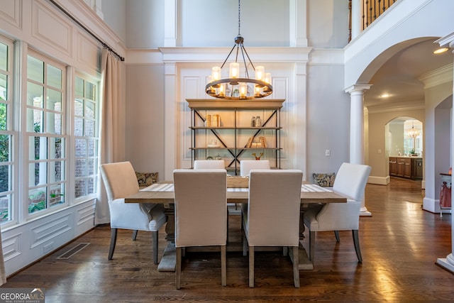 dining space with arched walkways, a healthy amount of sunlight, visible vents, an inviting chandelier, and a high ceiling