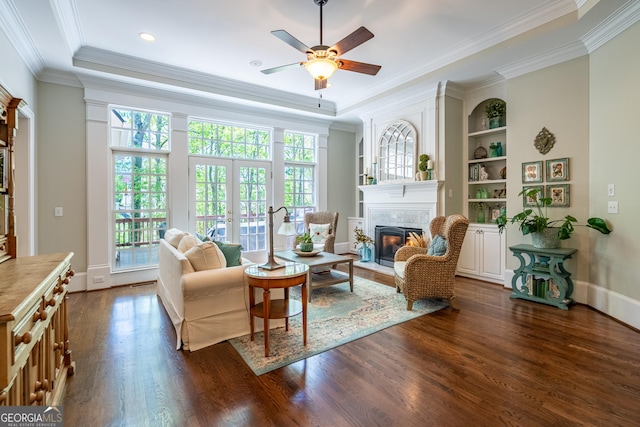 interior space featuring a tiled fireplace, a healthy amount of sunlight, crown molding, and dark wood-style flooring
