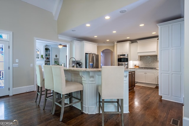 kitchen featuring stainless steel appliances, dark wood-style floors, visible vents, a breakfast bar, and premium range hood