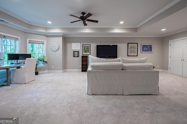 carpeted living room featuring ceiling fan, baseboards, ornamental molding, and a tray ceiling