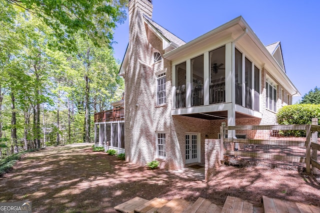 view of side of property with french doors, a sunroom, and a chimney
