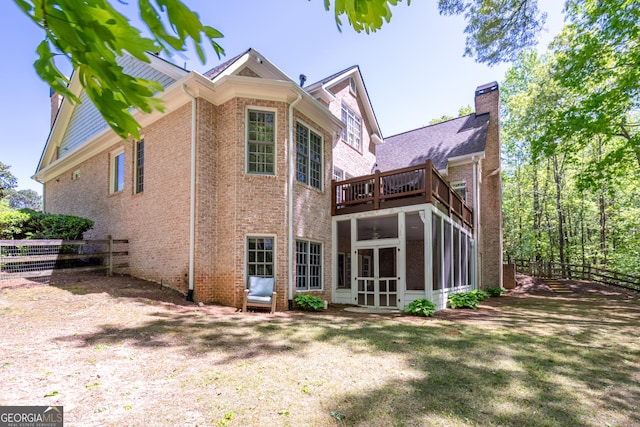 back of house with a chimney, a sunroom, fence, and a balcony